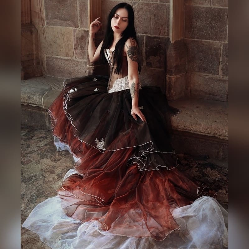 This stunning creation combines a luxurious shantung silk overbust corset with delicate white lace and brown rhinestone accents. The corset is expertly crafted, offering adjustable sizing with a front busk and lace-up back, reinforced with steel bones and lined with soft silk for both comfort and structure.
The showstopper is the voluminous skirt, made of three layers of delicate organza that flow with elegance and grace